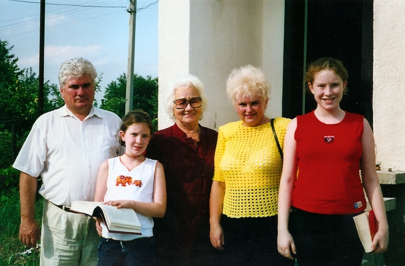 four people standing next to each other near a house