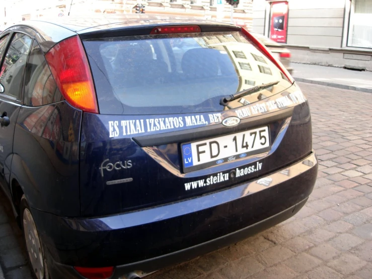 a small blue car is parked on the sidewalk