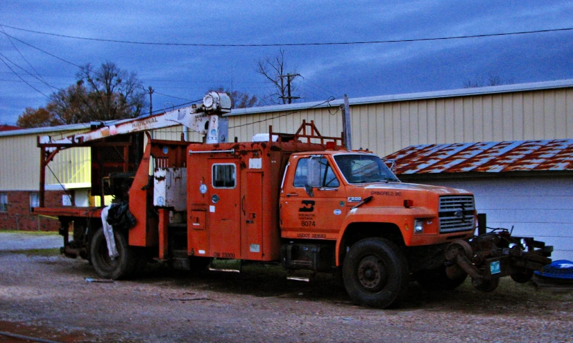 an orange truck parked outside a building near a tree