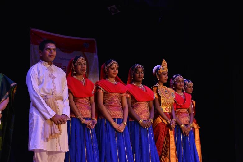 men in traditional attire stand at an edge for a performance