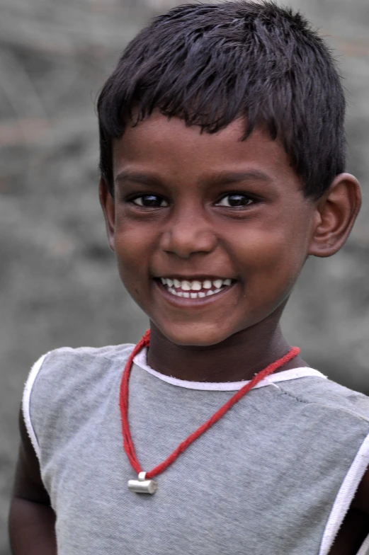an african child smiling, with an orange beaded necklace