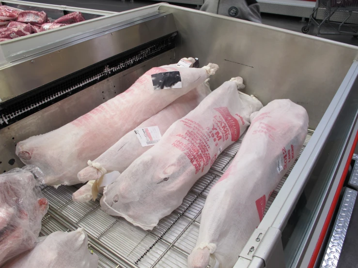 six bundles of raw and uncooked meat sitting on a conveyor belt