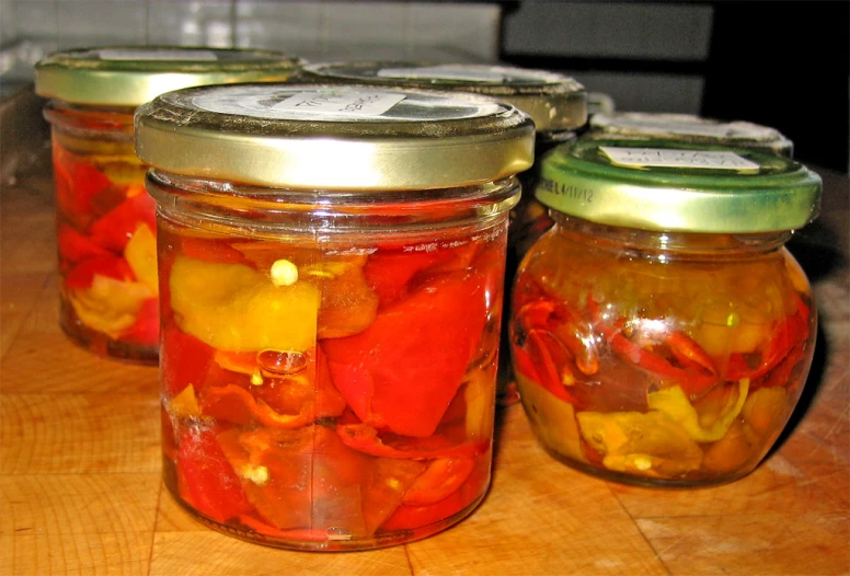 three jars with pickles and other food items in it