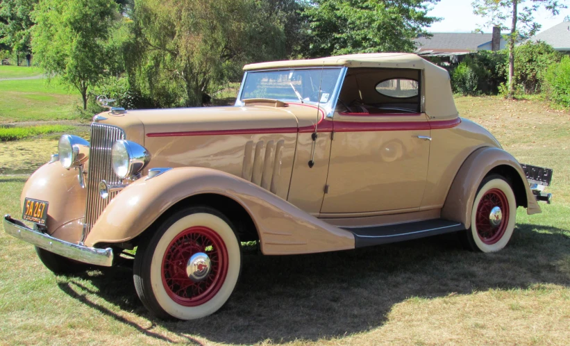 the front side of an old tan car on grass