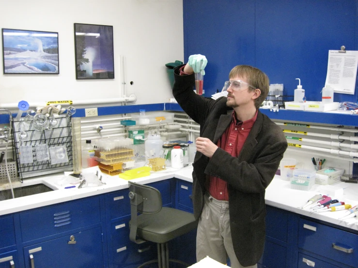 a young man in a lab is standing near cabinets with blue walls