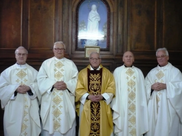 a group of men in white and gold robes with an ornate statue in the background