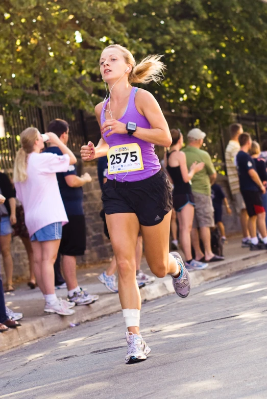 a woman running down a street in front of a crowd