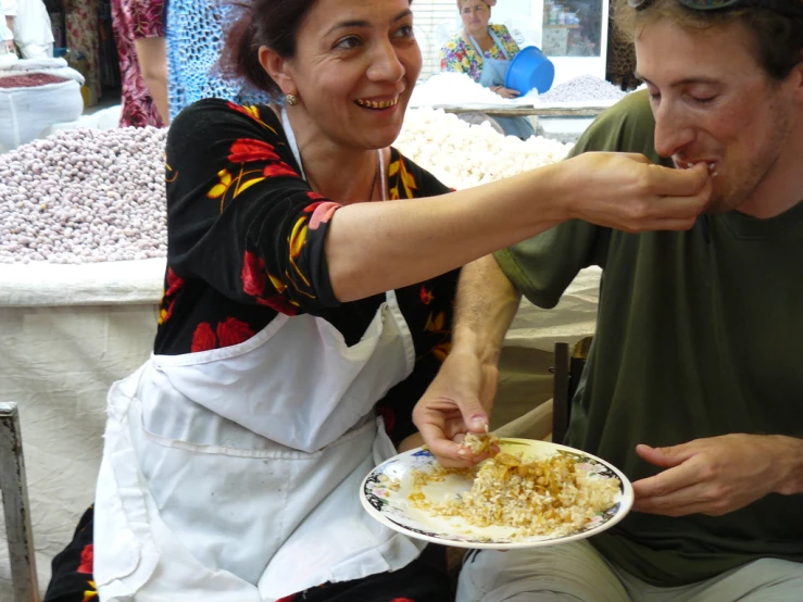 a man and woman eating food in a market