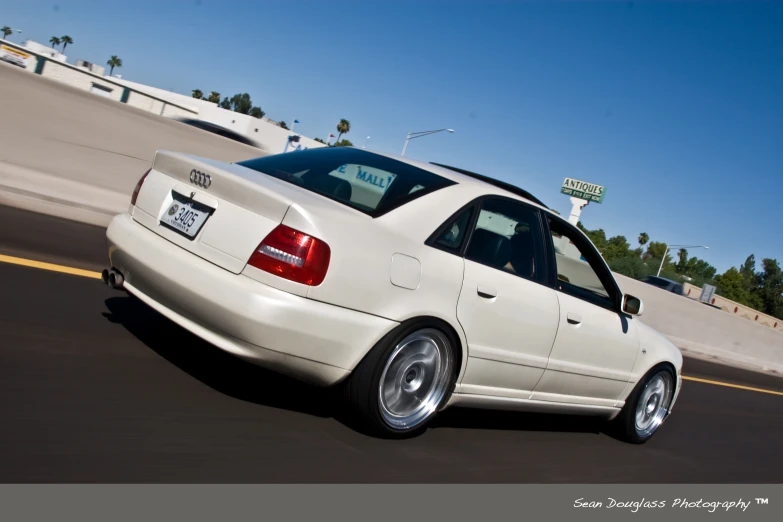 a white car drives on the road near a freeway