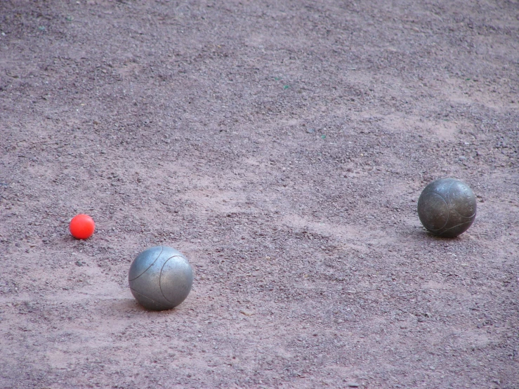 two balls laying on the ground on top of some sand