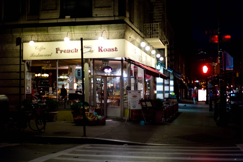 an open corner store at night, in the middle of a city