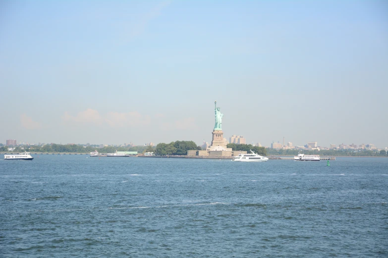 boats and ships are in the water near a statue of liberty