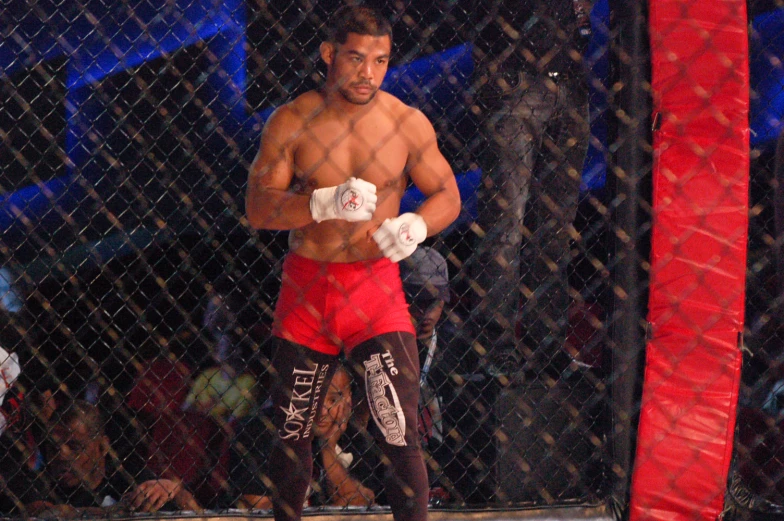 a fighter posing with his glove and standing in the middle of a cage
