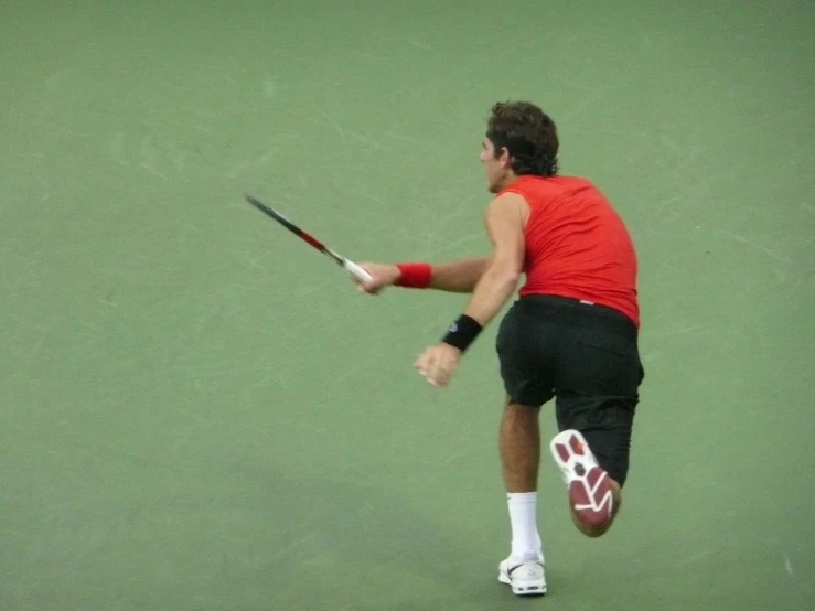 a male tennis player dressed in black and red is hitting a ball