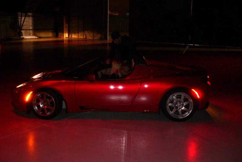 a red sports car parked in a garage with it's doors open