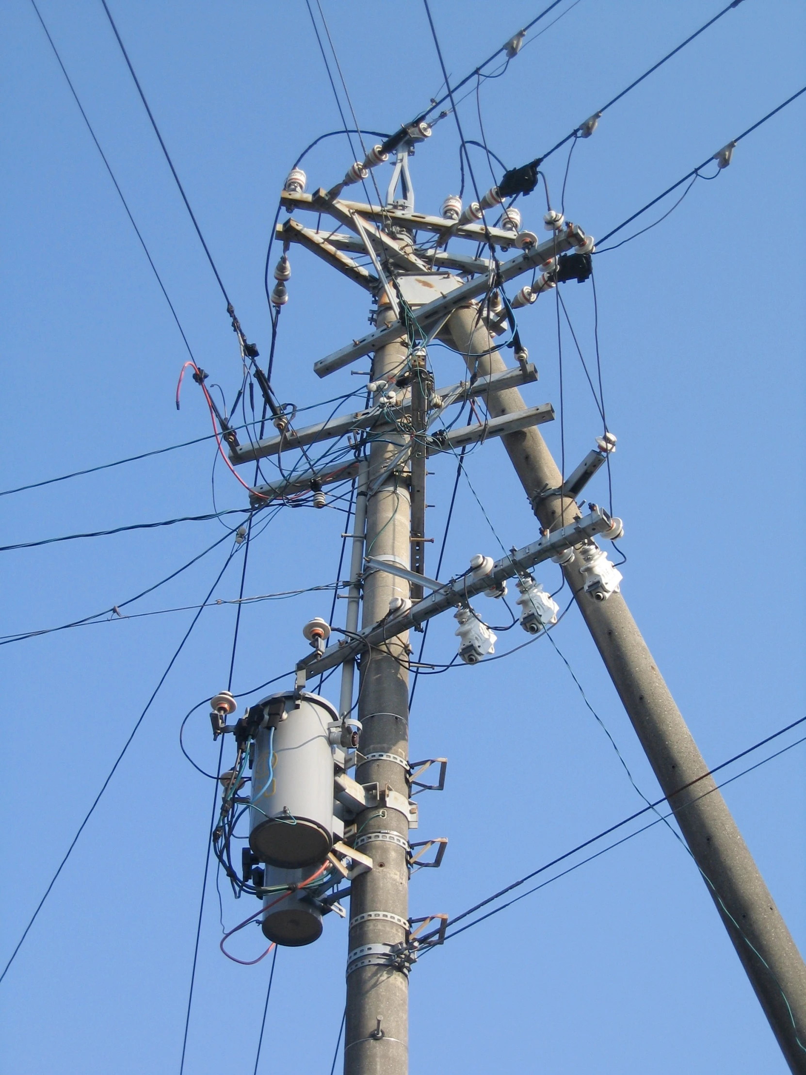 the power lines of a utility pole with an electrical outlet at the bottom