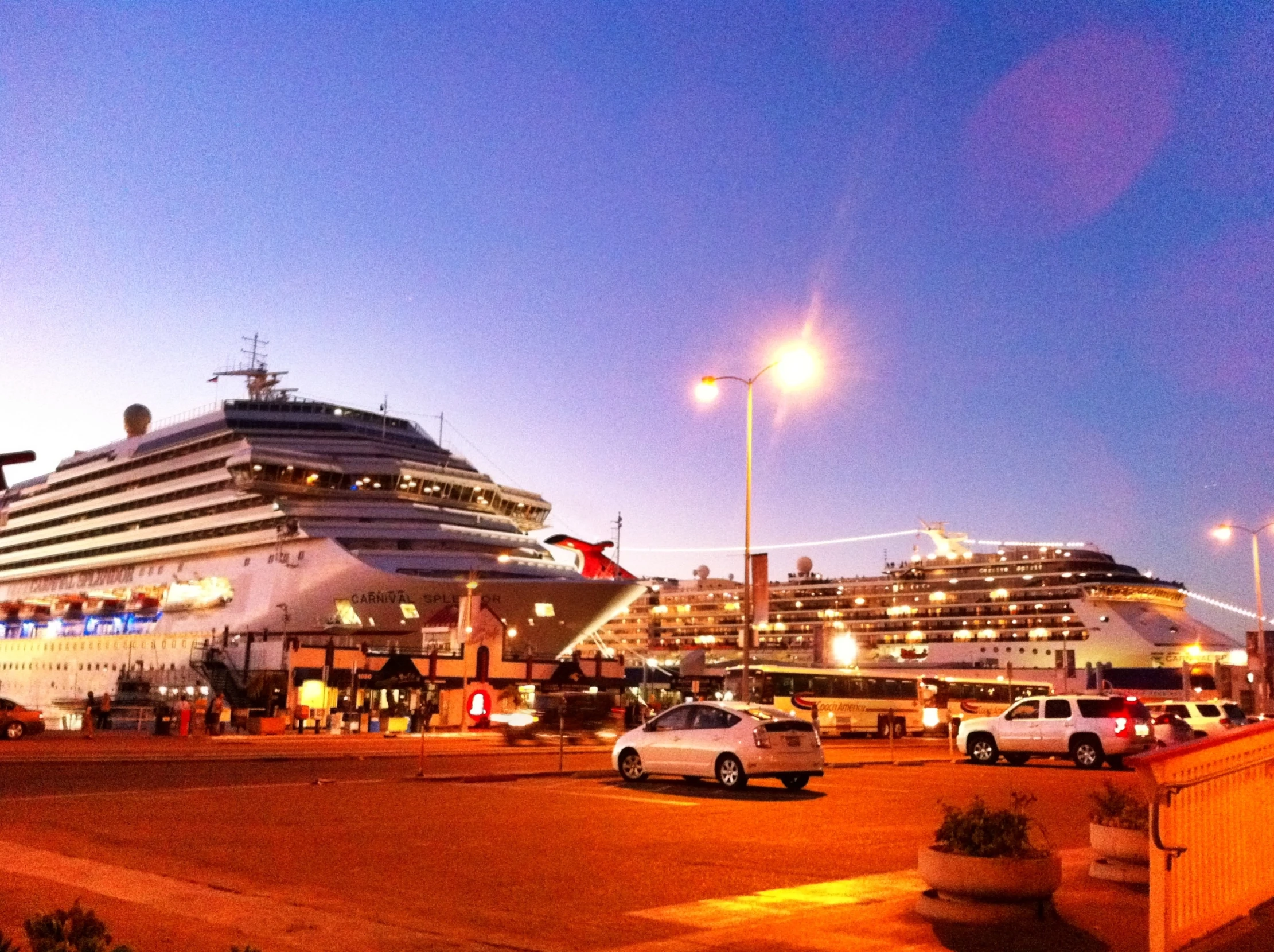 a cruise ship in the distance with many cars parked on the street