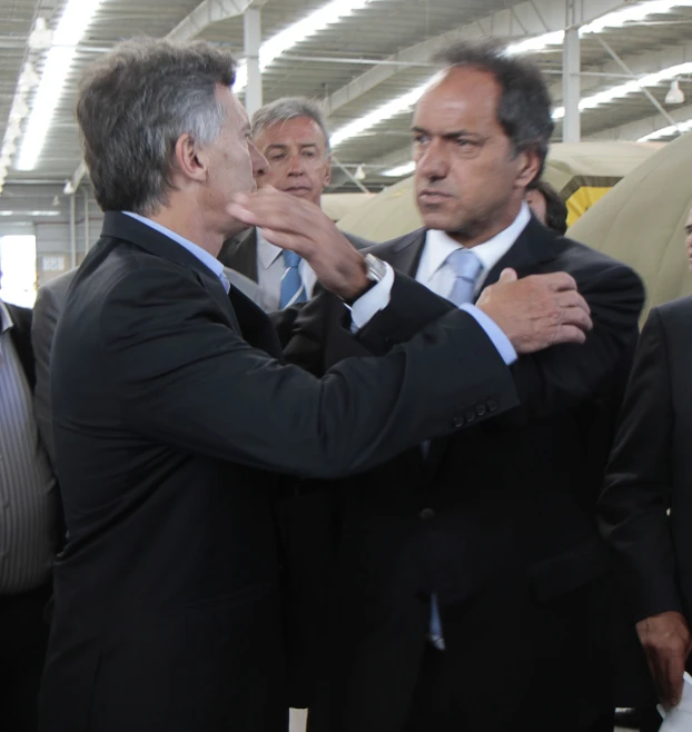 several men are standing in a warehouse while one is adjusting the others jacket