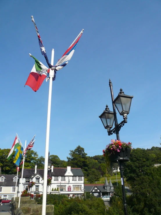 several flags blowing on a pole and in front of a building