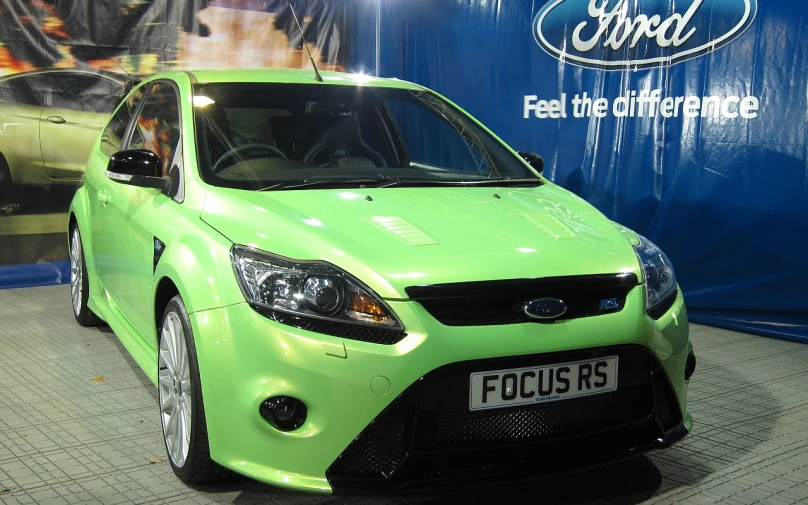 a green ford focus is parked in front of a large sign