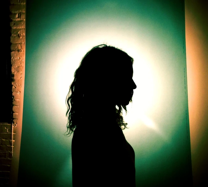 the silhouette of a woman with curly hair is standing in front of the light