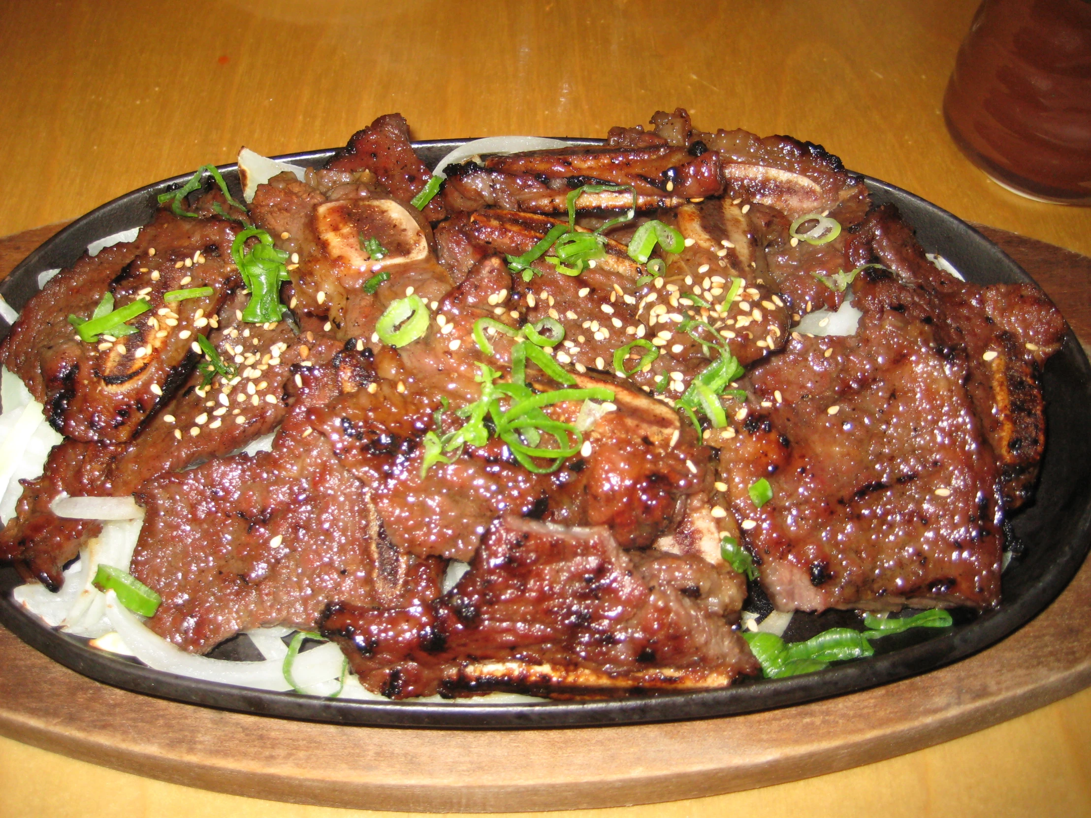 a black plate with some meat and green onions