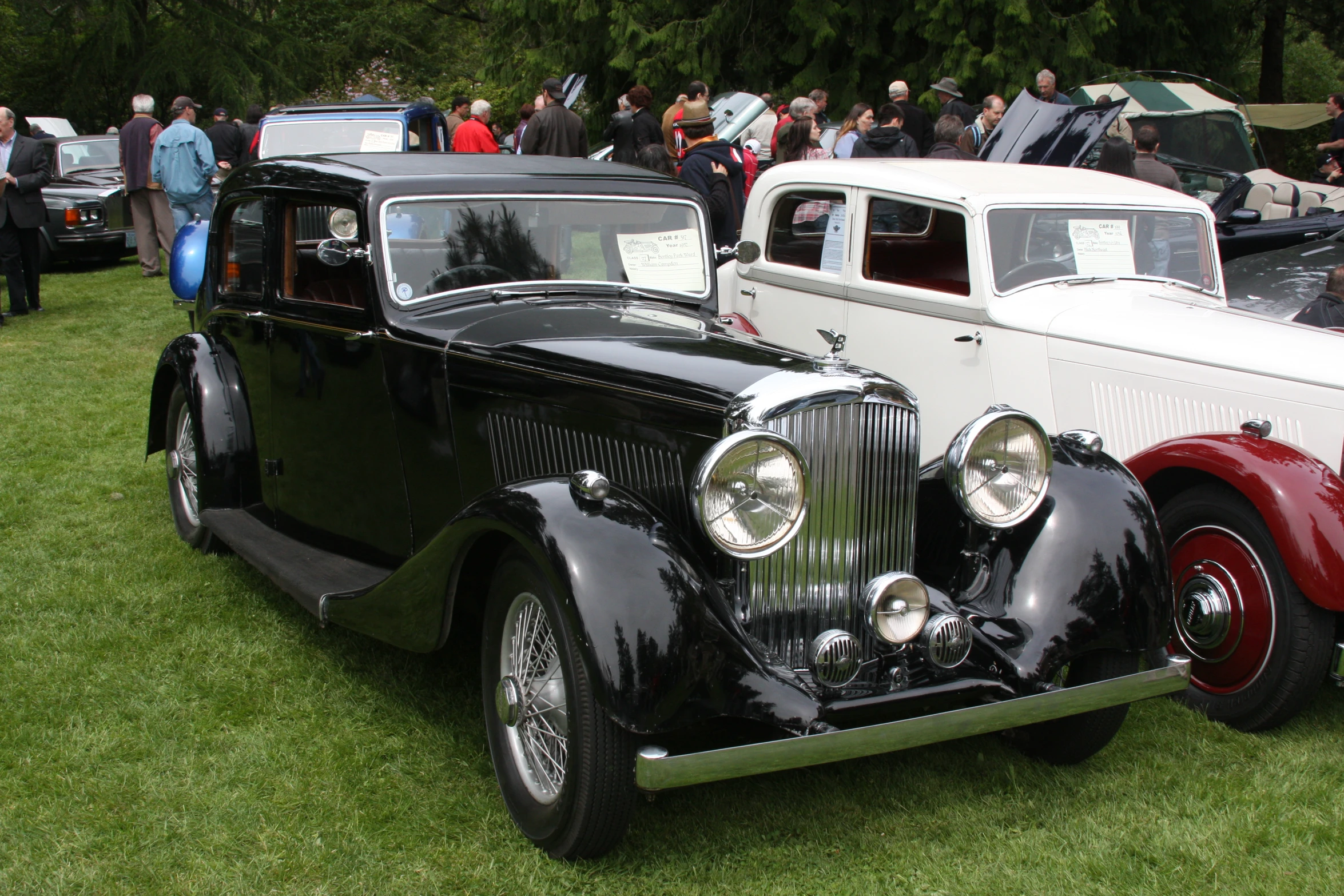 two cars parked in front of each other at a car show