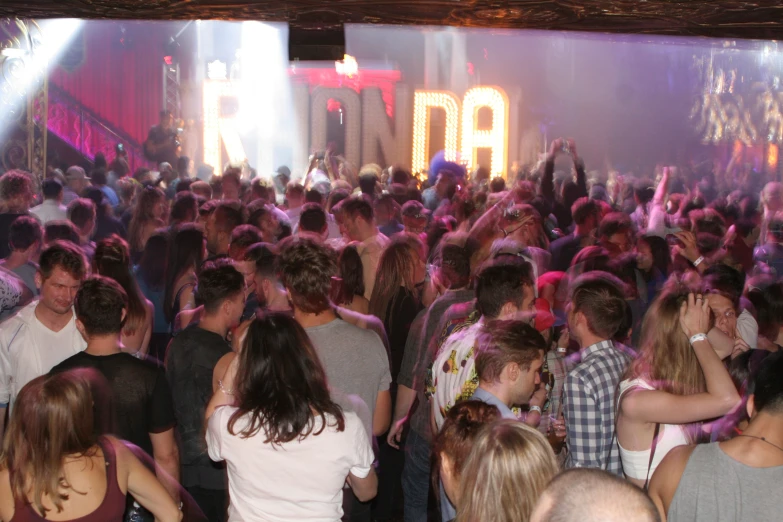 people stand around in front of a lit up stage