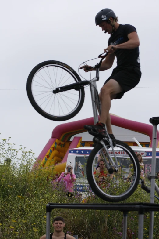 a man on a bicycle is performing stunts in front of people