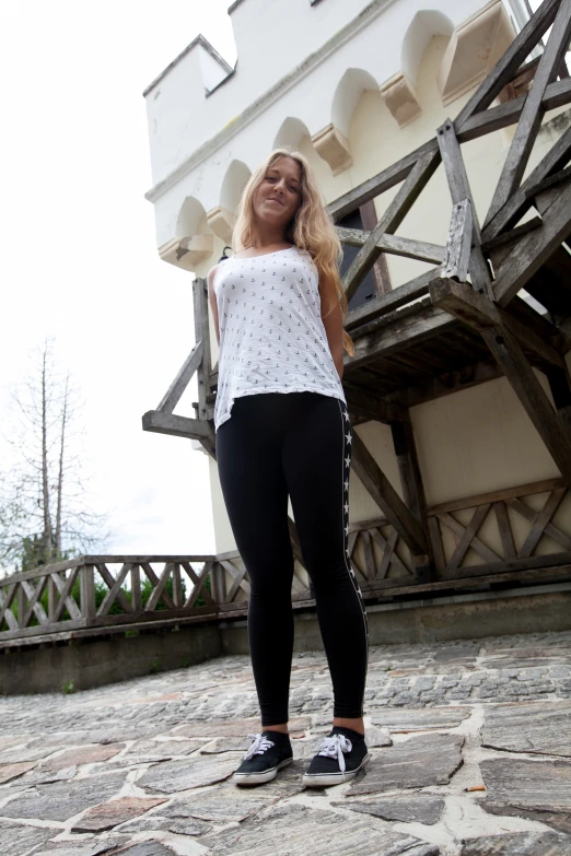 a woman in white top and black pants posing