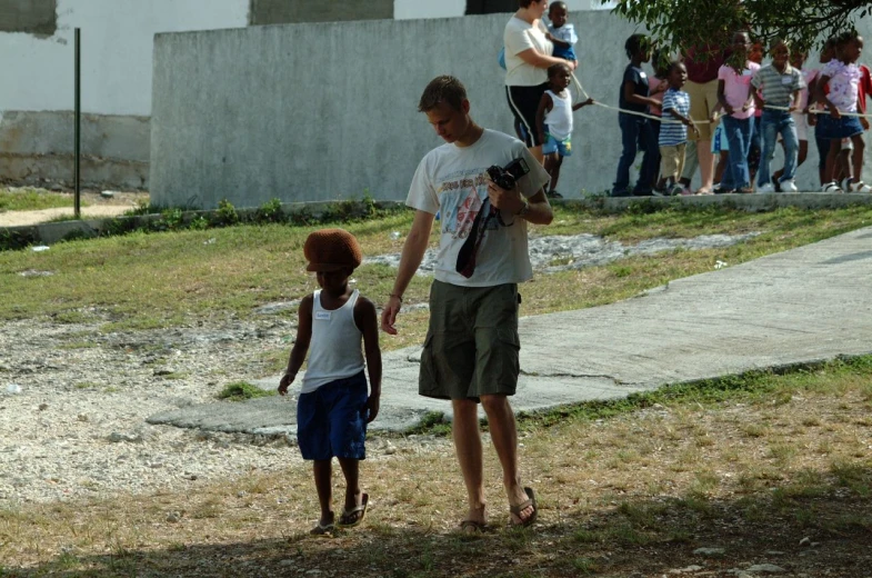 a man holds hands with a small child as adults watch