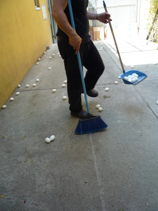 a man cleaning his sidewalk with a broom