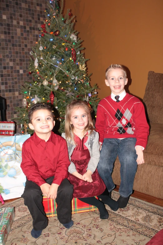 two s are dressed in red and sitting on presents