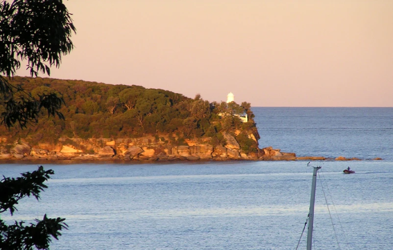 an island off the coast with trees in the foreground