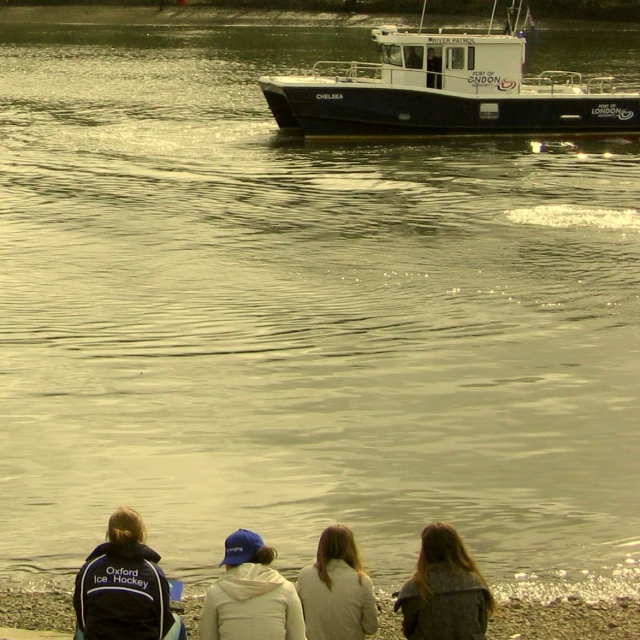 a group of people sitting on the beach in front of a boat