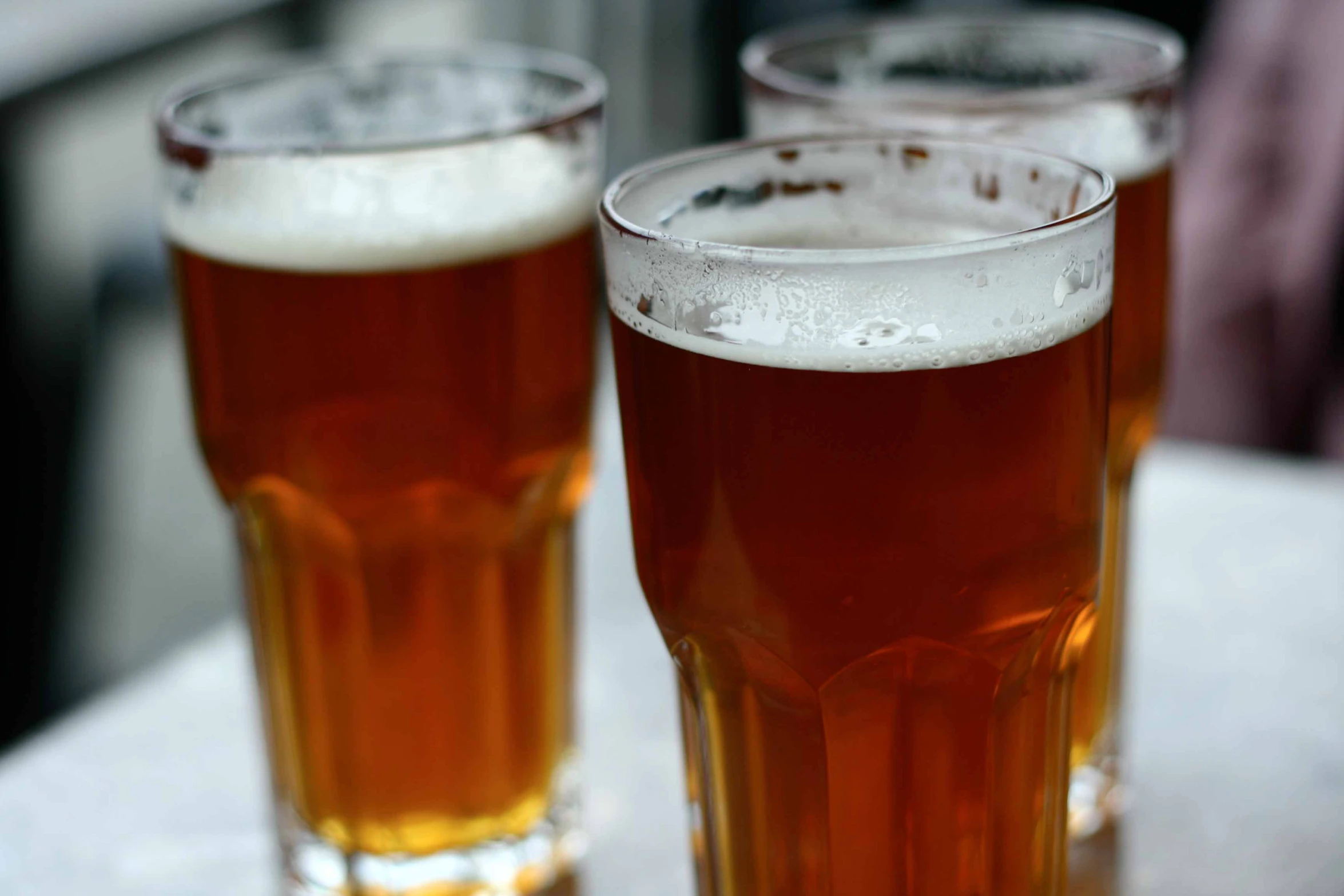 two glasses of beer sitting on top of a white table