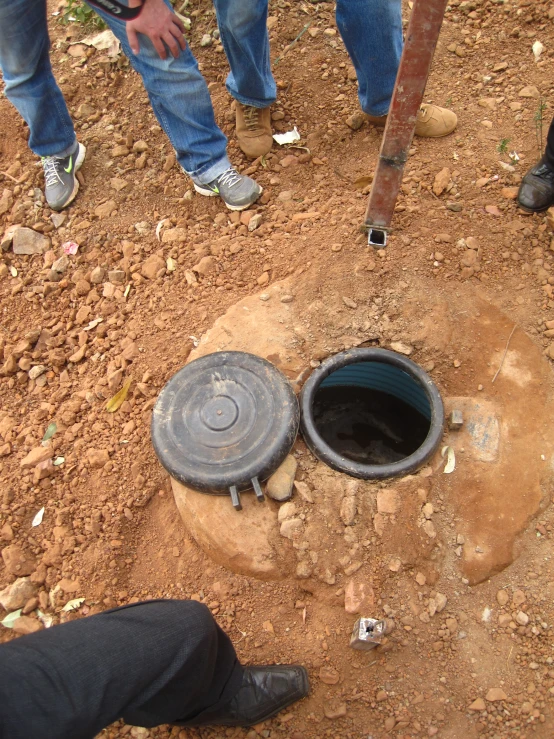 a black metal open toilet sits in the dirt