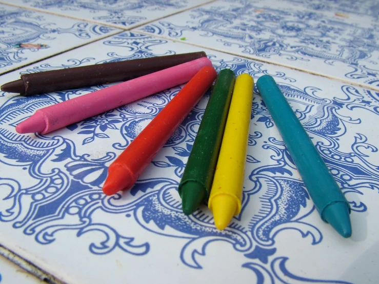 a few crayons laying on top of a blue and white pattern