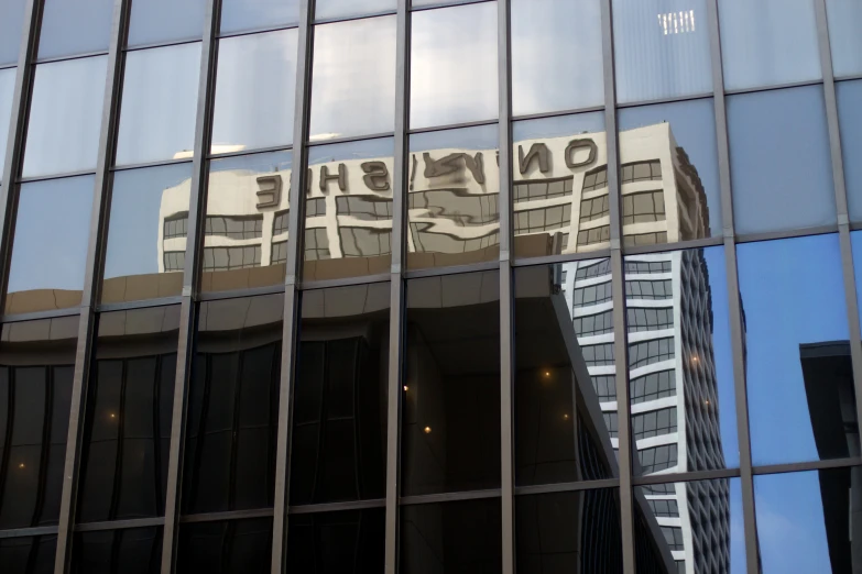 the reflection of two buildings on the glass facade