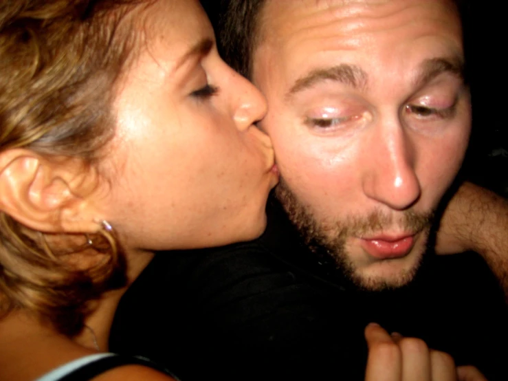 a man kissing a woman while she kisses her face