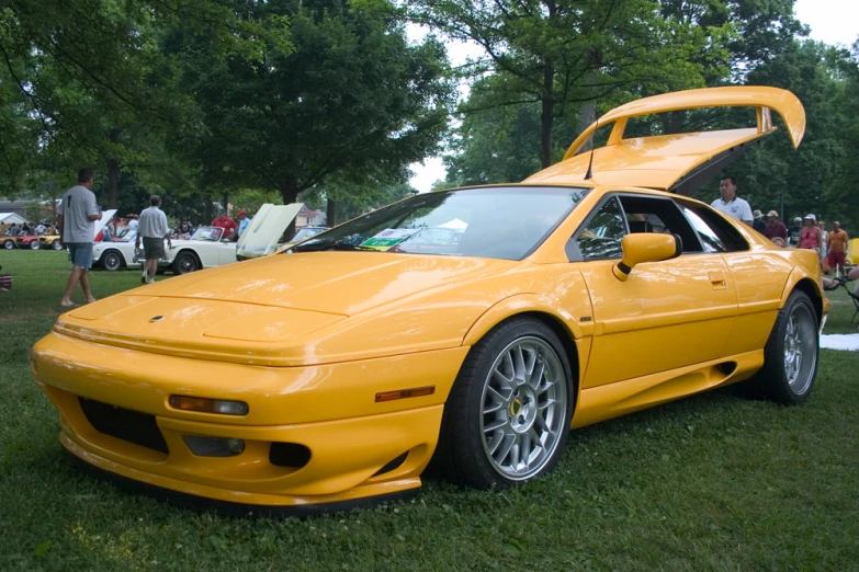 an orange sports car sits in the grass