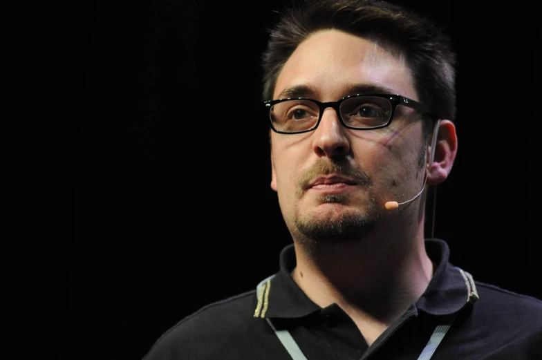 a man in a black shirt with a mustache and glasses on