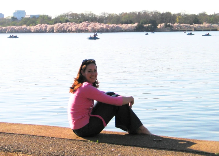 a woman sitting on the edge of the dock, on a sunny day