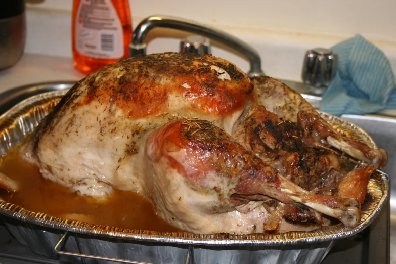 a whole chicken sitting in a pan of brown liquid