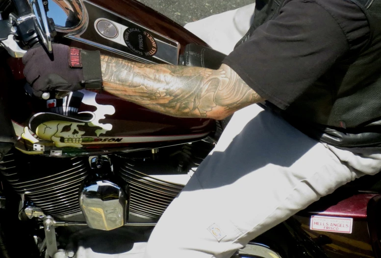 a man with tattoos on his arms and arm rests on a parked motorcycle