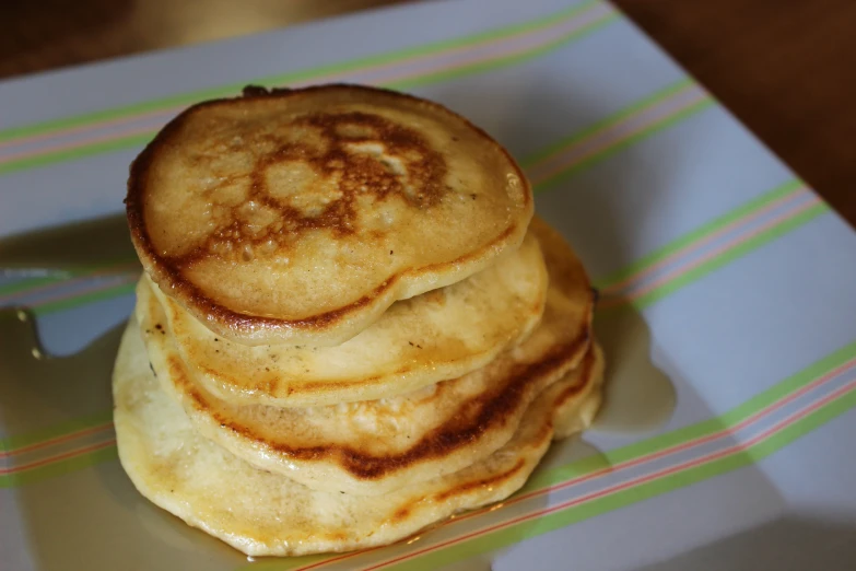 a white plate topped with pancakes covered in syrup