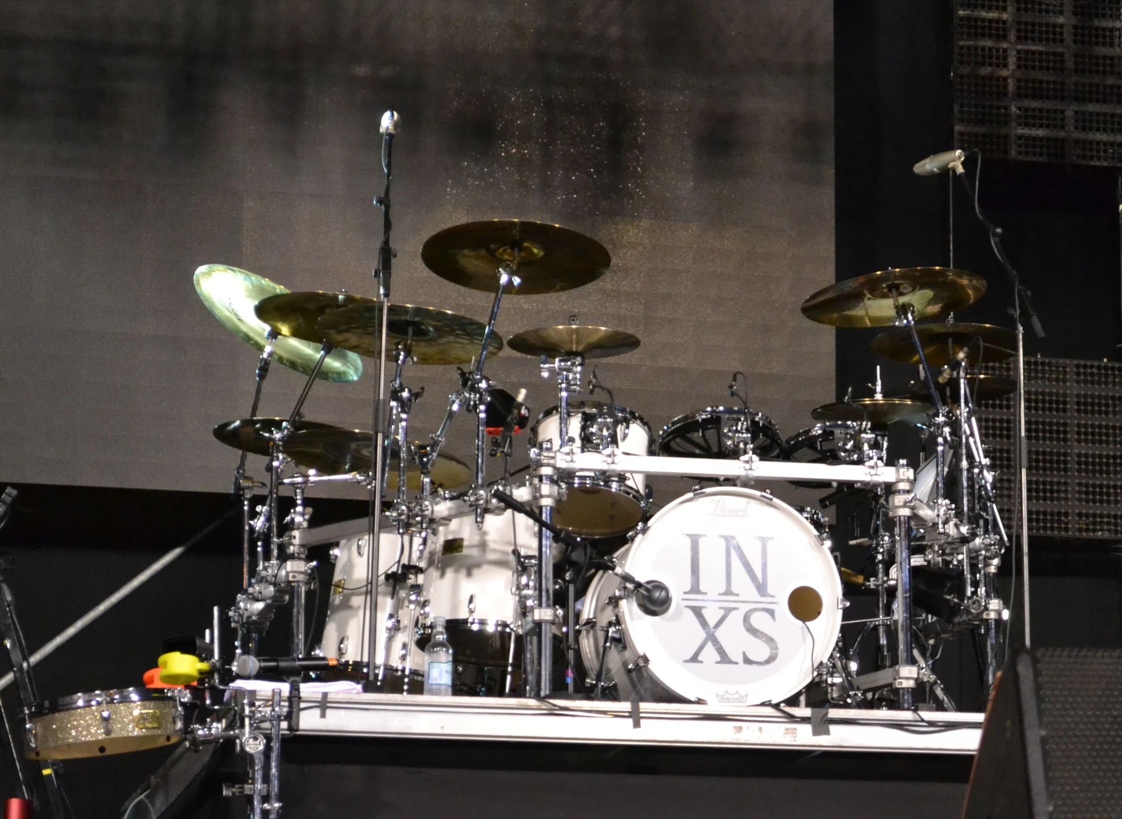 a drummer with lots of white drums playing on stage