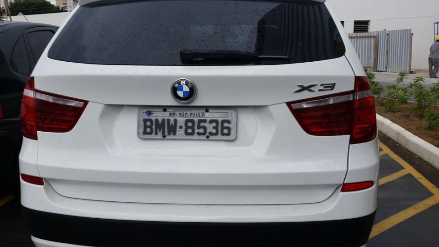 there is a white bmw car with a license plate in a parking space