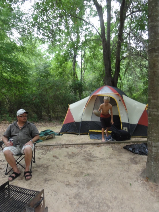 an older couple sitting in chairs outside of a tent