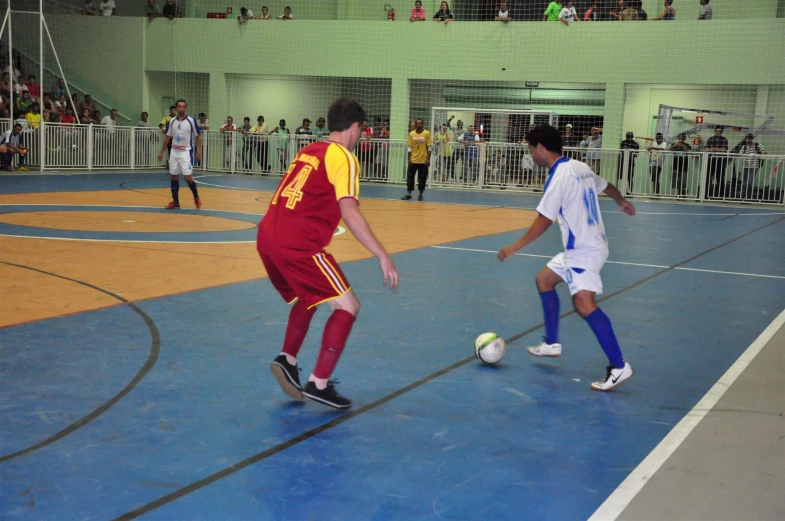 young men play a game of soccer while in a crowd watch